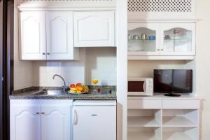 a white kitchen with a sink and a microwave at Apartamentos Masaru in Puerto de la Cruz