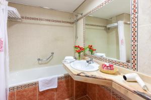 a bathroom with a sink and a tub and a mirror at Apartamentos Masaru in Puerto de la Cruz