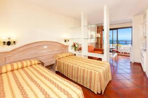 a hotel room with two beds and a balcony at Apartamentos Masaru in Puerto de la Cruz
