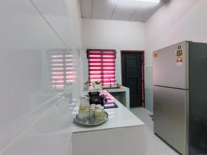 a kitchen with a white counter and a refrigerator at Nariz Homestay Kuala Ketil in Kuala Ketil +3 photos