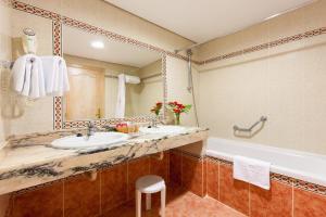 a bathroom with two sinks and a tub and a mirror at Apartamentos Masaru in Puerto de la Cruz