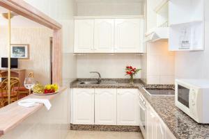 a kitchen with white cabinets and a bowl of fruit on the counter at Apartamentos Masaru in Puerto de la Cruz