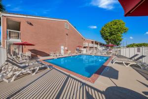 a swimming pool with chairs and a building at Motel 6-Plano, TX - Plano Northeast in Plano