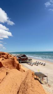 a sandy beach with a building and the ocean at Pousada Capitólio 04 Canoa Quebrada in Canoa Quebrada