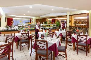 a man standing in a restaurant with tables at Apartamentos Masaru in Puerto de la Cruz