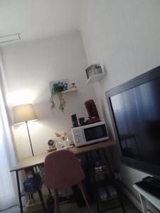 a room with a desk with a television and a table with a lamp at loue chambre chez l'habitant in Saint-Victoret +13 photos