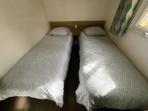 two beds in a small room next to a window at Mobil home Premium super cosy entre Lac et Océan in Hourtin +1 photo