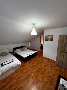 two beds in a room with wooden floors at Casa NIB Calimanesti in Călimăneşti