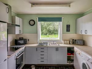 eine Küche mit weißen Schränken und einem Fenster in der Unterkunft Lamastar in Woolfardisworthy