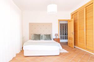 ein Schlafzimmer mit einem weißen Bett in einem Zimmer in der Unterkunft T3 Praia del Rey, piscina e vista mar, Óbidos, A7 in Óbidos