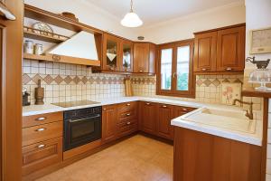 cocina con armarios de madera, fregadero y fogones en Mila House, en Mouresi
