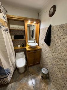 ein Badezimmer mit Toilette, Waschbecken und Spiegel in der Unterkunft Aur House in Puerto Natales