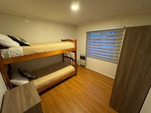 ein kleines Zimmer mit 2 Etagenbetten und einem Fenster in der Unterkunft Aur House in Puerto Natales