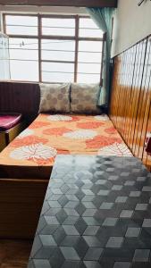 a bedroom with a bed with an orange and gray comforter at Tashi taksang homestay in Darjeeling