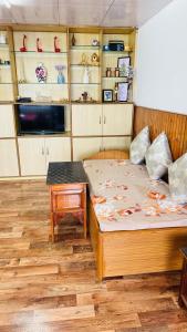 a bedroom with a bed and a table and shelves at Tashi taksang homestay in Darjeeling