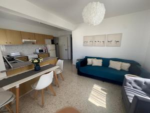 a living room with a blue couch and a kitchen at Riana Latchi Apartment in Polis Chrysochous