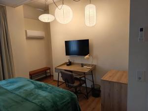 a bedroom with a desk with a television and a bed at Renatus Apartments in Eschau