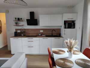 a kitchen with white cabinets and a table with chairs at Studio Cosy in Feuquières