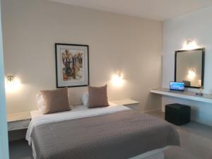 a white bedroom with a bed and a mirror at Nomad Résidence in Hammamet