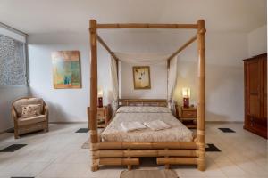 a bedroom with a wooden canopy bed with a chair at Villa Playa del Duque in Adeje +26 photos