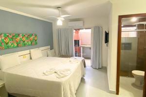 a bedroom with a white bed and a bathroom at RESIDENCIAL MAR GALILÉIA in Porto Seguro +37 photos
