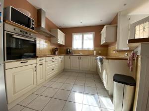 a kitchen with white cabinets and a tile floor at Maison paisible in Gujan-Mestras