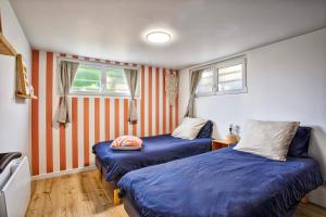 2 camas en una habitación con rayas anaranjadas y blancas en Maison des Flots, en Luc-sur-Mer
