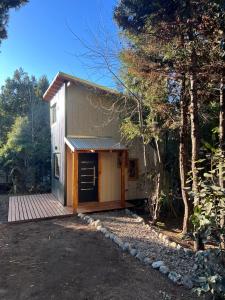 a small house with a wooden deck in the woods at Niwa tiny house in San Carlos de Bariloche