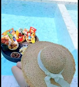 a person wearing a straw hat with a basket of food in a swimming pool at The Tropical Pool Villas Ao Nang Group Krabi in Ao Nang Beach