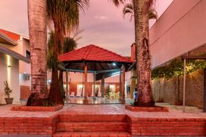 un bâtiment avec un kiosque entre deux palmiers dans l'établissement Nana Suites, à Foz do Iguaçu
