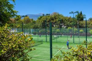 a group of people playing tennis on a tennis court at Apartamentos Masaru in Puerto de la Cruz