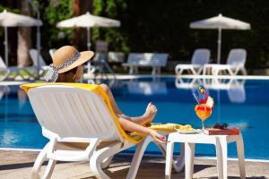 a woman sitting in a chair next to a pool at Apartamentos Masaru in Puerto de la Cruz