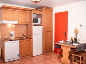 a kitchen with wooden cabinets and a white refrigerator at Studio cabine 6 personnes avec balcon, parking et casier à ski - FR-1-504-124 in Uvernet-Fours