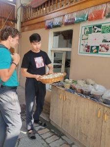a man holding a basket in front of a food stand at JOMIY Guest House in Margilan