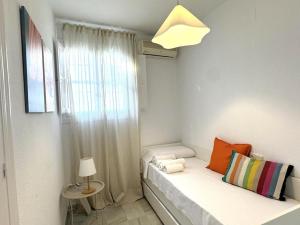 Habitación blanca pequeña con cama y ventana en Sibs Sanlucar Bajamar - Bright & Central, en Sanlúcar de Barrameda