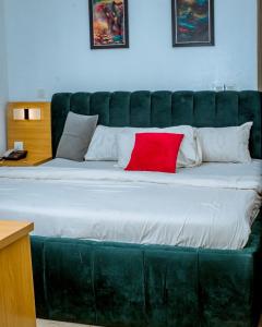 a large green bed with a red pillow on it at Padelia Hotels Ltd in Nsukka
