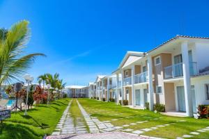 a row of houses on a lawn with palm trees at RESIDENCIAL MAR GALILÉIA in Porto Seguro
