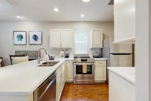 Stylish & sun-filled retreat with large patio & fireplace - near beaches & golf في فرناندينا بيتش: مطبخ مع دواليب بيضاء واجهزة ستانلس ستيل