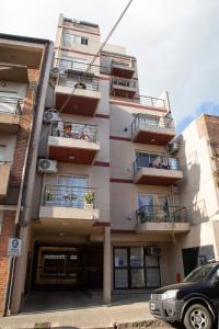a building with balconies and a car parked in front at Centro Peru in Paraná