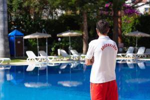 a man standing in front of a swimming pool at Apartamentos Masaru in Puerto de la Cruz