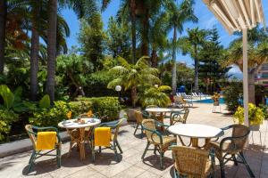 an outdoor patio with tables and chairs and a pool at Apartamentos Masaru in Puerto de la Cruz