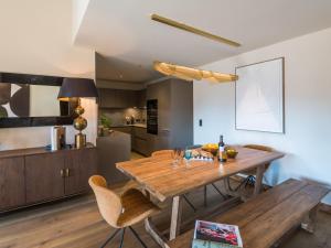 a kitchen and dining room with a wooden table and chairs at Appartement de Luxe Neuf avec Terrasse au Cœur des Gets, Proche des Pistes et Commerces - FR-1-598-153 in Les Gets