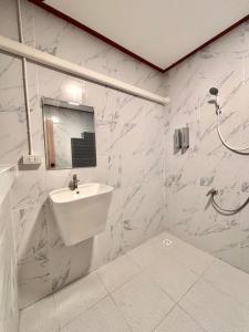 a white bathroom with a sink and a shower at Our Time Staycation in Ban Chak Makham