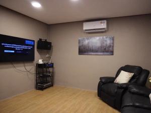 a living room with a black couch and a television at Our Time Staycation in Ban Chak Makham +1 photo