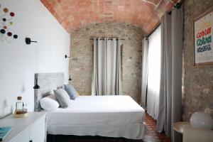 a bedroom with a white bed and a brick wall at Casa Merceditas in Corçà