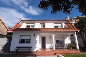 a white house with a bench in front of it at Playa de Cesantes in Pontevedra