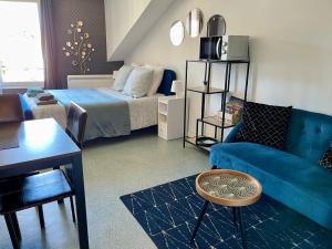 a living room with a blue couch and a bed at PYRENE HOLIDAYS - Résidence La Fontaine - Studios cozy à 10mn à pied des thermes in Bagnères-de-Bigorre