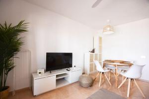 ein Wohnzimmer mit Fernseher und Tisch und Stühlen in der Unterkunft Oasis Duna Casa Maho in Corralejo