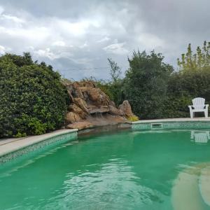 una piscina con una sedia seduta accanto a una cascata di Complejo miligamapa a Villa Carlos Paz