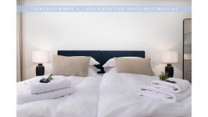 a bedroom with two beds with white sheets and towels at Apartment Leinetal - bester Schlafkomfort in hochwertiger Hotelbettwäsche, 3 Zimmer - große Küche, Duschbad & Parkplatz in Northeim